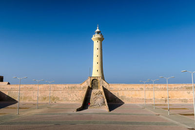 Street light by building against clear blue sky