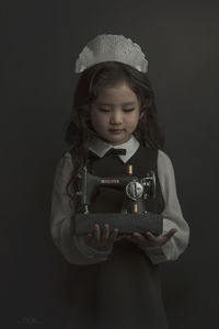 Girl holding camera over black background