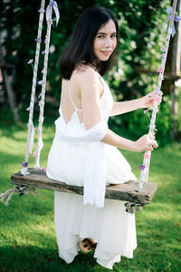 Portrait of woman sitting on swing at park