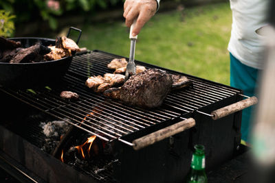 Midsection of man preparing food on barbecue grill