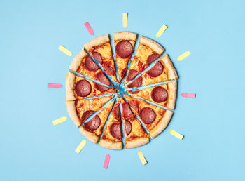 Sliced pizza salami and empty post-it for every portion, on retro blue background. pepperoni pizza.