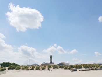 Lighthouse by beach against sky