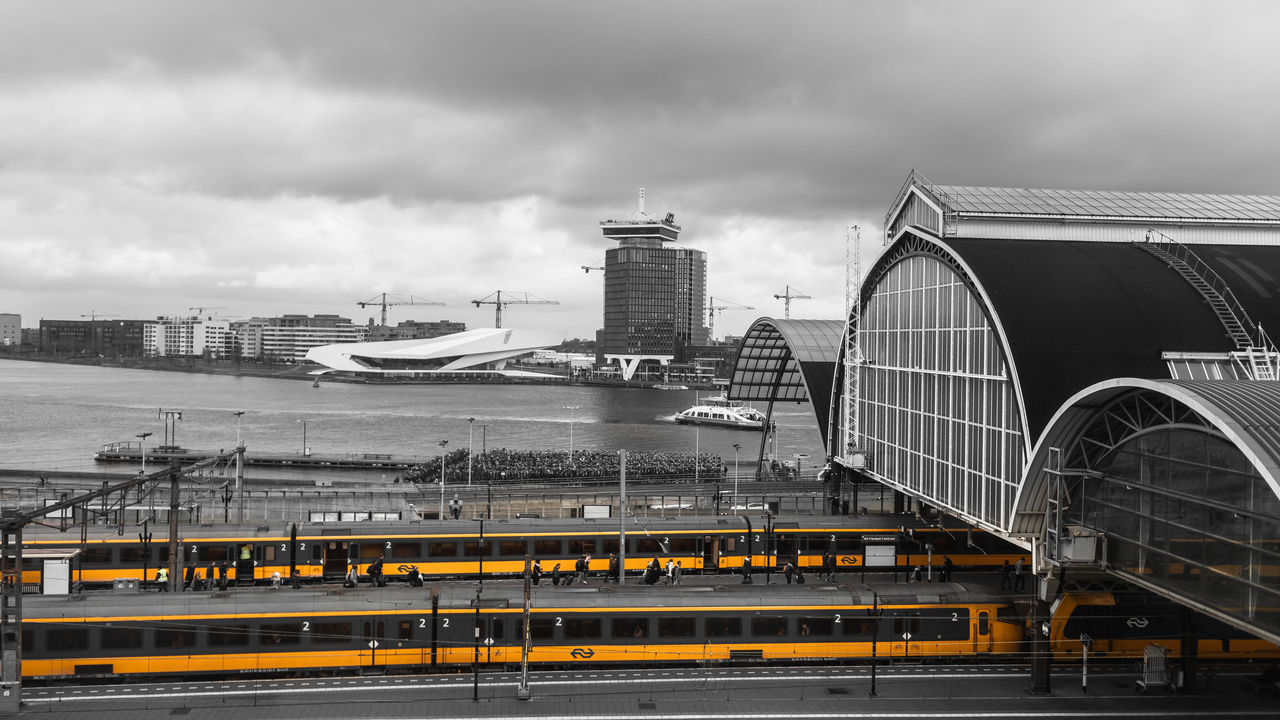 TRAIN ON BRIDGE AGAINST CLOUDY SKY