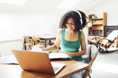 Young woman using laptop while sitting on sofa at home