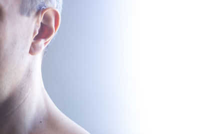 Cropped image of shirtless man standing against white background