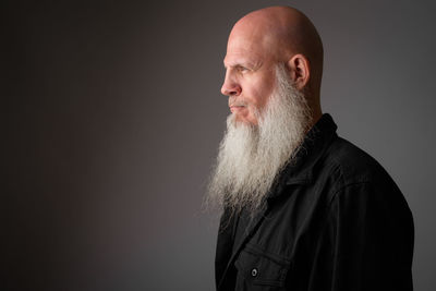 Portrait of man standing against black background