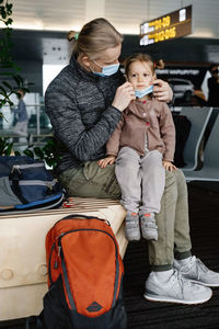 Father putting face mask on childs face at the airport. man protects girl from coronavirus at public