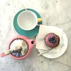 High angle view of cupcake in plate by cup on marble