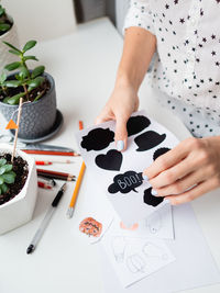 Woman writes boo on decorative black stickers for chalks. handmade decorations for halloween.