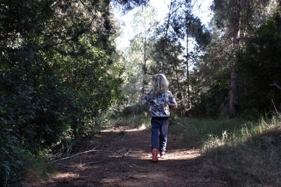 Rear view of girl standing on street amidst trees