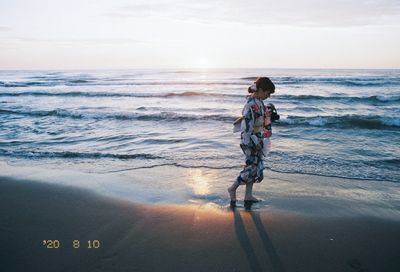 Full length of boy on beach against sky