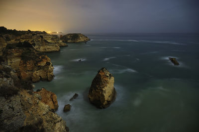Rocks on sea shore against sky