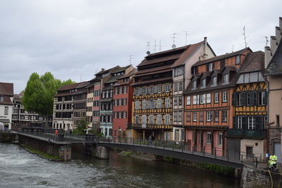 Bridge over river by buildings against sky