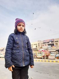 Portrait of young woman standing against sky