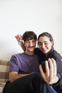 Young couple on sofa taking selfie