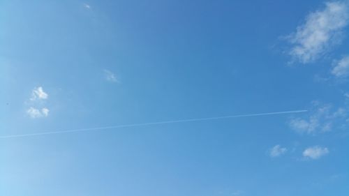 Low angle view of vapor trails against blue sky