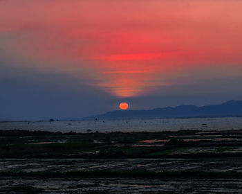 Scenic view of sea against dramatic sky during sunset