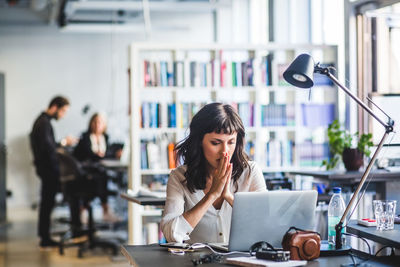 Young woman using mobile phone while sitting on table