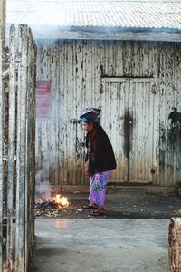 Side view of woman standing against building