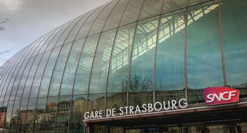 Low angle view of text on glass building against sky