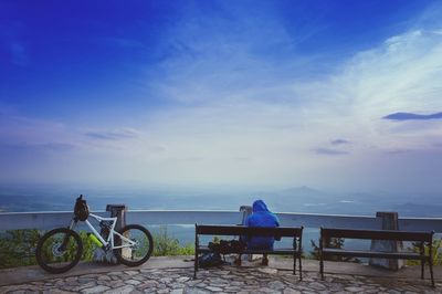 Bicycle sitting on bench by sea against blue sky