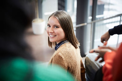 Smiling young student sitting with friends in university