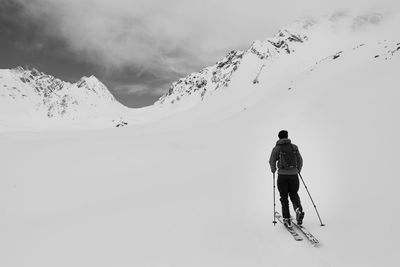 Rear view of man skiing on snowcapped mountain against sky