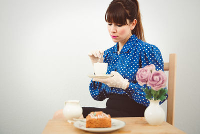 Young woman sitting by coffee cup on table