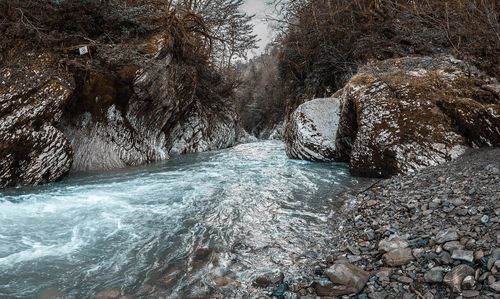 Stream flowing through rocks during winter