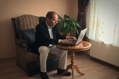 Man using mobile phone while sitting on sofa at home