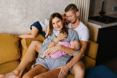 Portrait of mother and daughter sitting on sofa at home