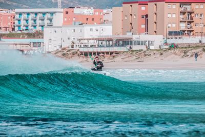 Man kitesurfing in sea against buildings in city