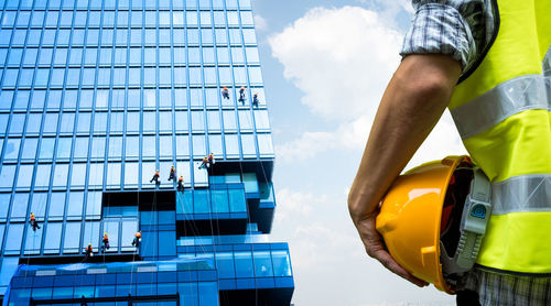 Low angle view of men working against sky