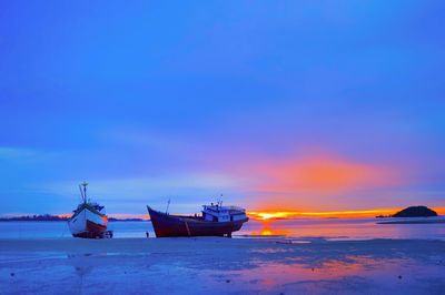 Boat moored on sea against sky at sunset
