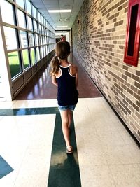 Full length rear view of woman walking on tiled floor