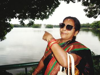 Portrait of man wearing sunglasses against lake