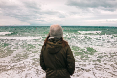 Rear view of man looking at sea shore against sky