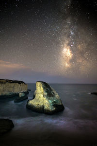 Rock formation on sea against sky at night