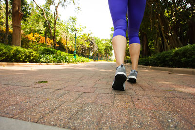 Low section of woman running on footpath