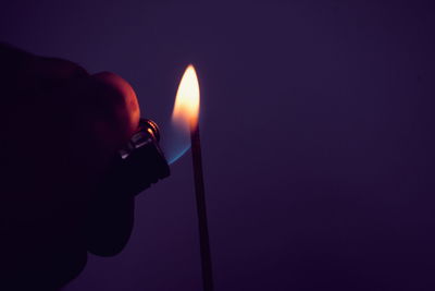Close-up of hand holding lit candle