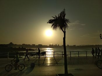 Silhouette people on beach against sky during sunset