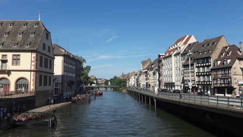 Canal in town against sky