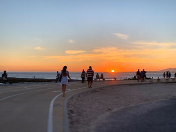 People on beach against sky during sunset