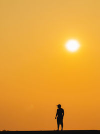 Silhouette man standing against orange sky