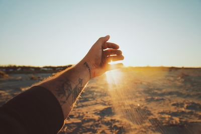 Midsection of person holding sun shining on land