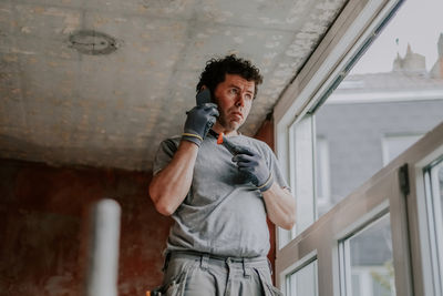 Construction worker talking on a smartphone near the window. person