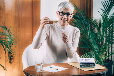 Portrait of woman holding camera on table