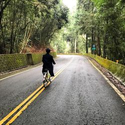 Rear view of man riding motorcycle on road