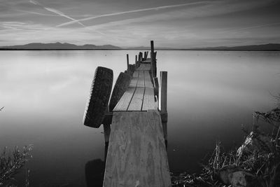 Tires hanging on old wooden jetty over salton sea lake against sky