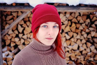 Portrait of young woman wearing knit hat against logs